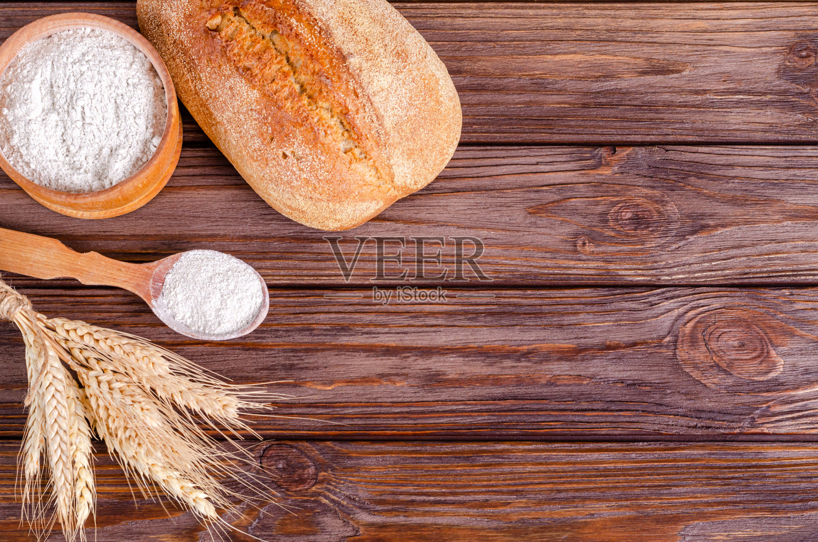 黑麦面包，面粉和一束小穗在木背景。照片摄影图片