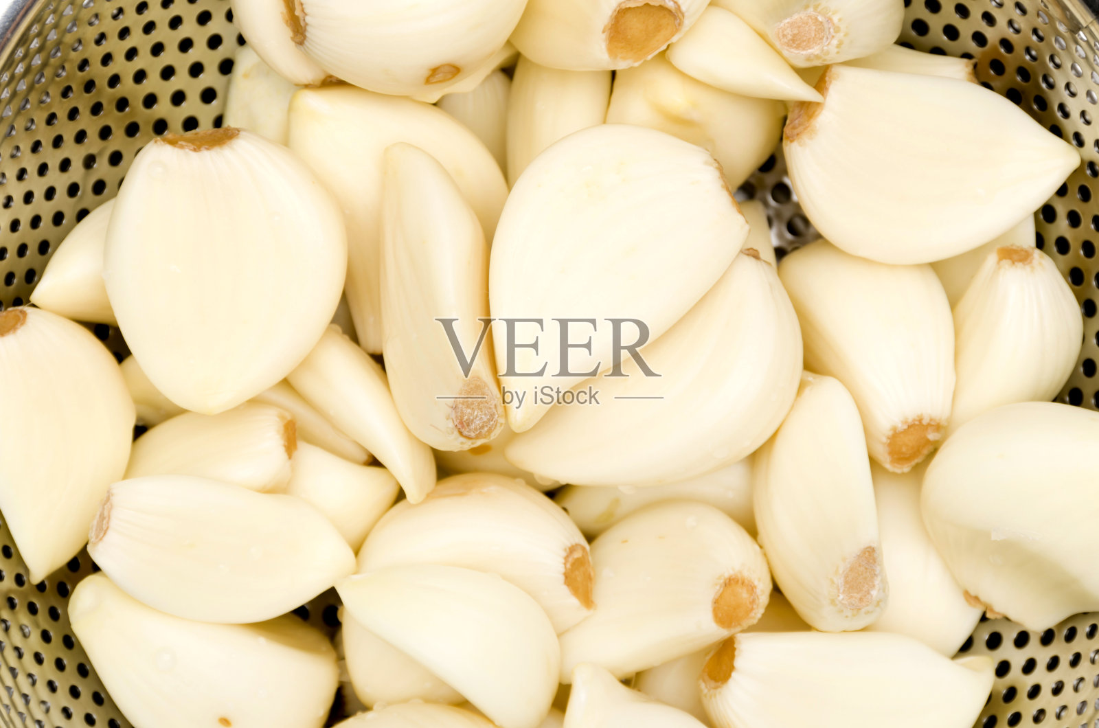 去皮的大蒜在不锈钢滤锅在白色的背景照片摄影图片