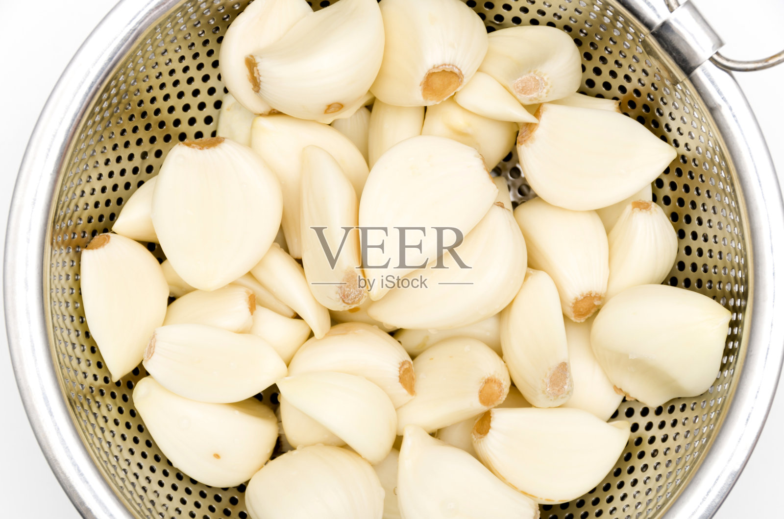 去皮的大蒜在不锈钢滤锅在白色的背景照片摄影图片