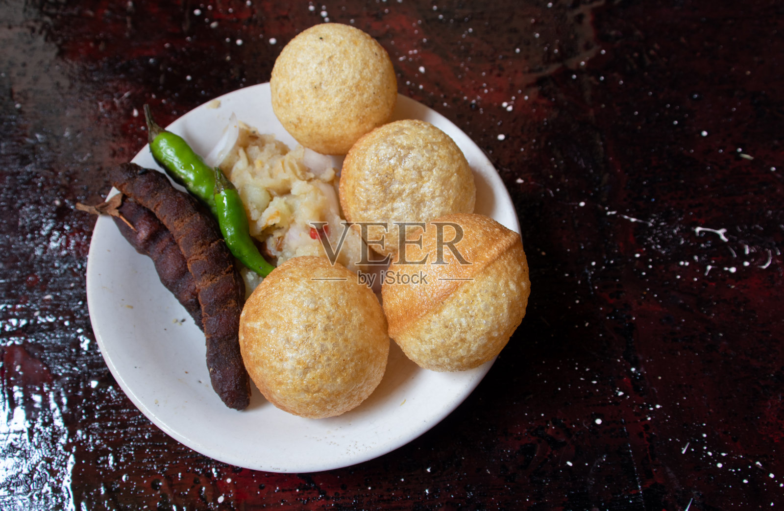 Panipuri or Golgappa with Spicy Potato Stuff, Tamaarind and Chili in a Plate Isolated on red Background with Copy Space，也被称为Phuchka, Paani Patashi, Gol Gappe, Gup Chup照片摄影图片