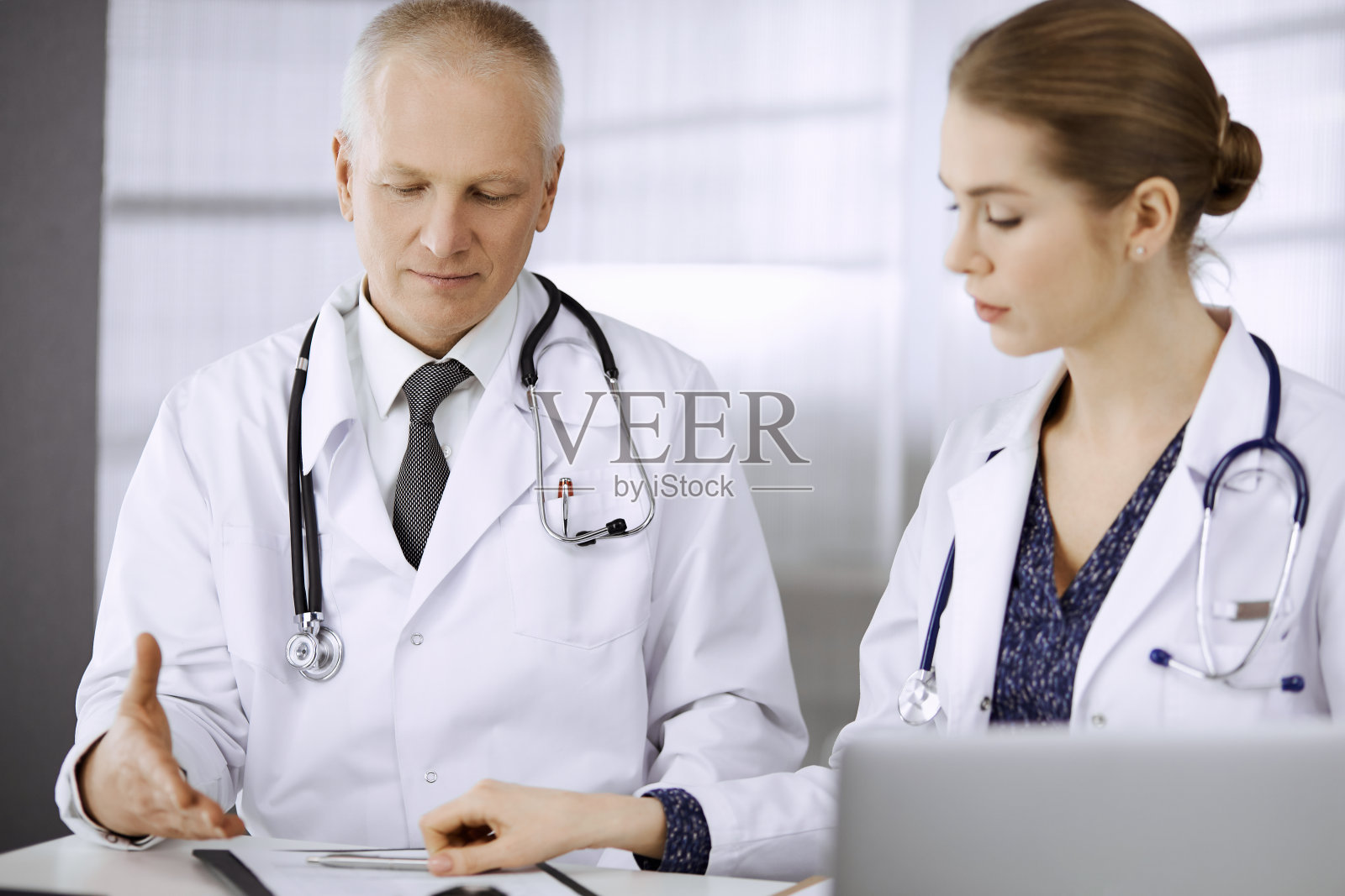 医生、同事和老年治疗师坐在诊所的工作场所讨论当前的疾病治疗。团队合作在医院。医疗保健理念照片摄影图片