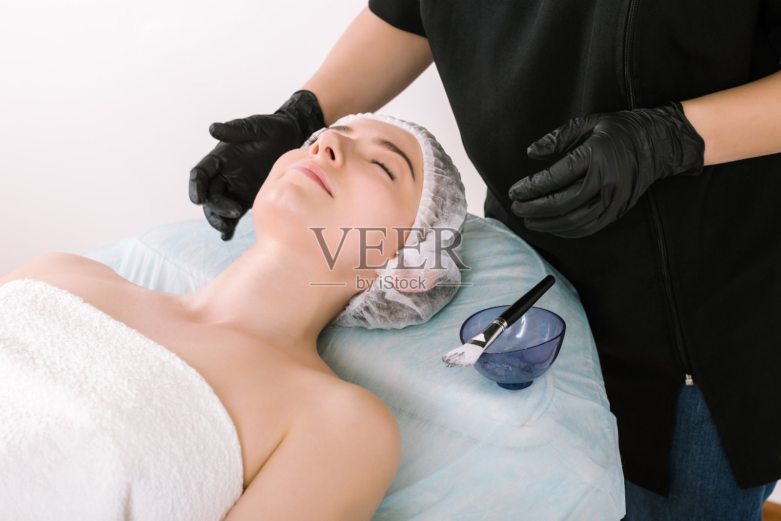 戴手套的美容师为女顾客做面部护理照片摄影图片
