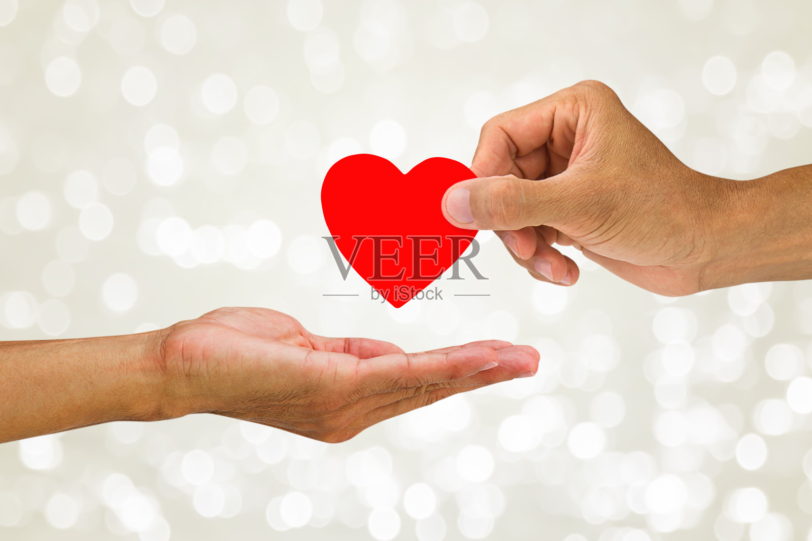手给红心上模糊白光闪闪的散景背景，帮助手的概念照片摄影图片