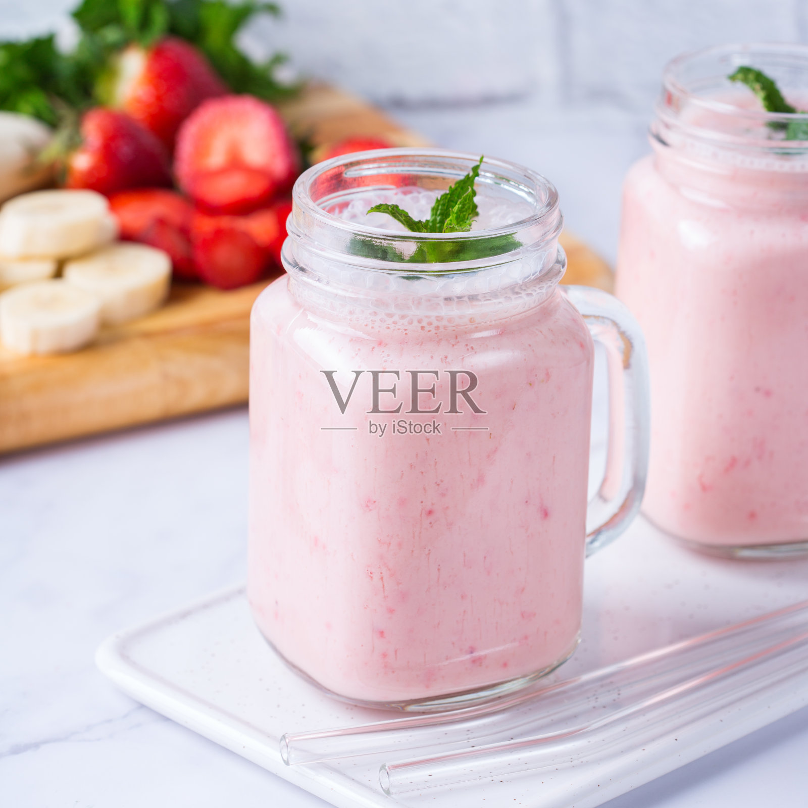 香蕉和草莓的粉色冰沙是健康的素食食谱照片摄影图片