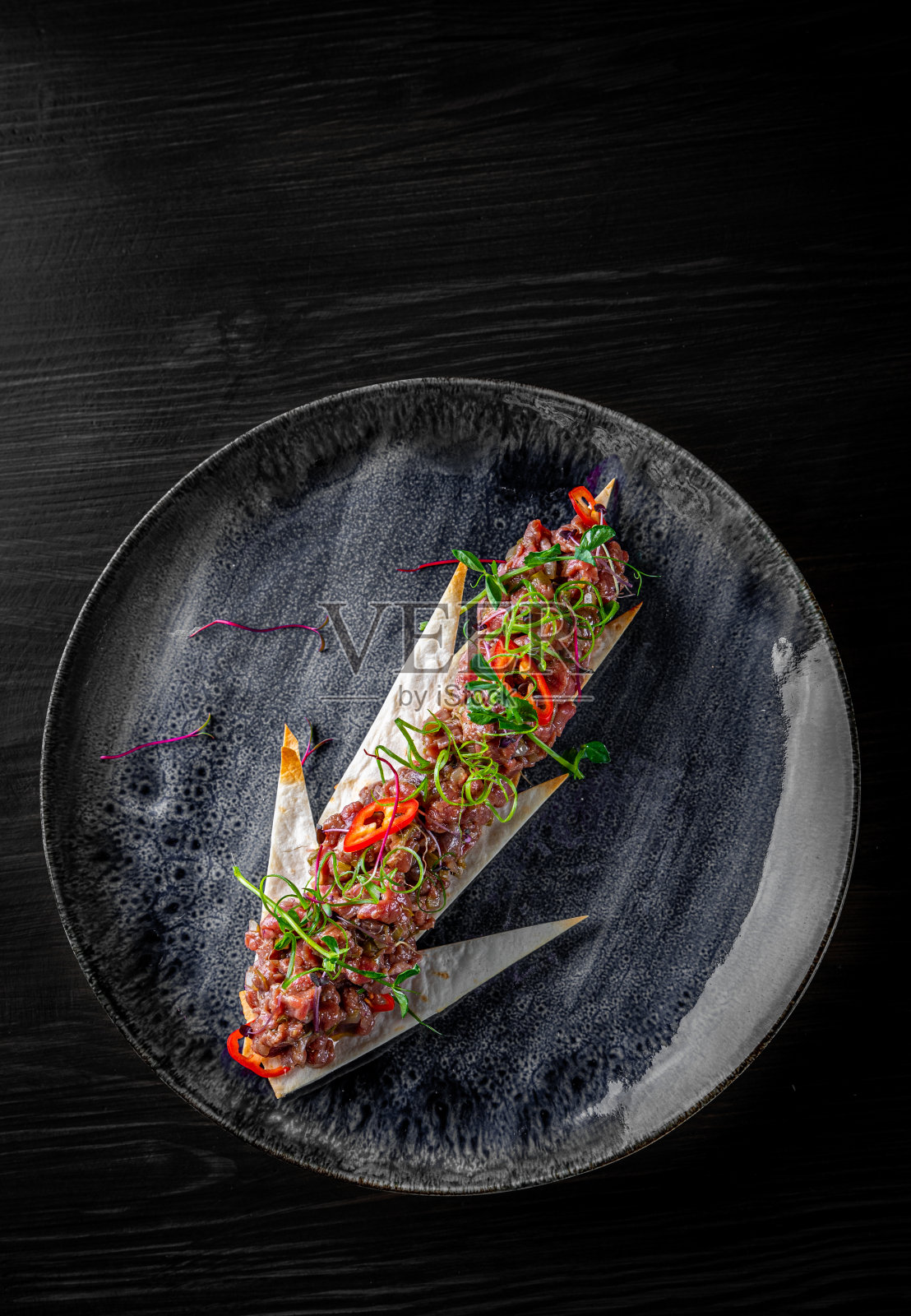 生牛肉鞑靼盘在黑色木制桌子的背景照片摄影图片