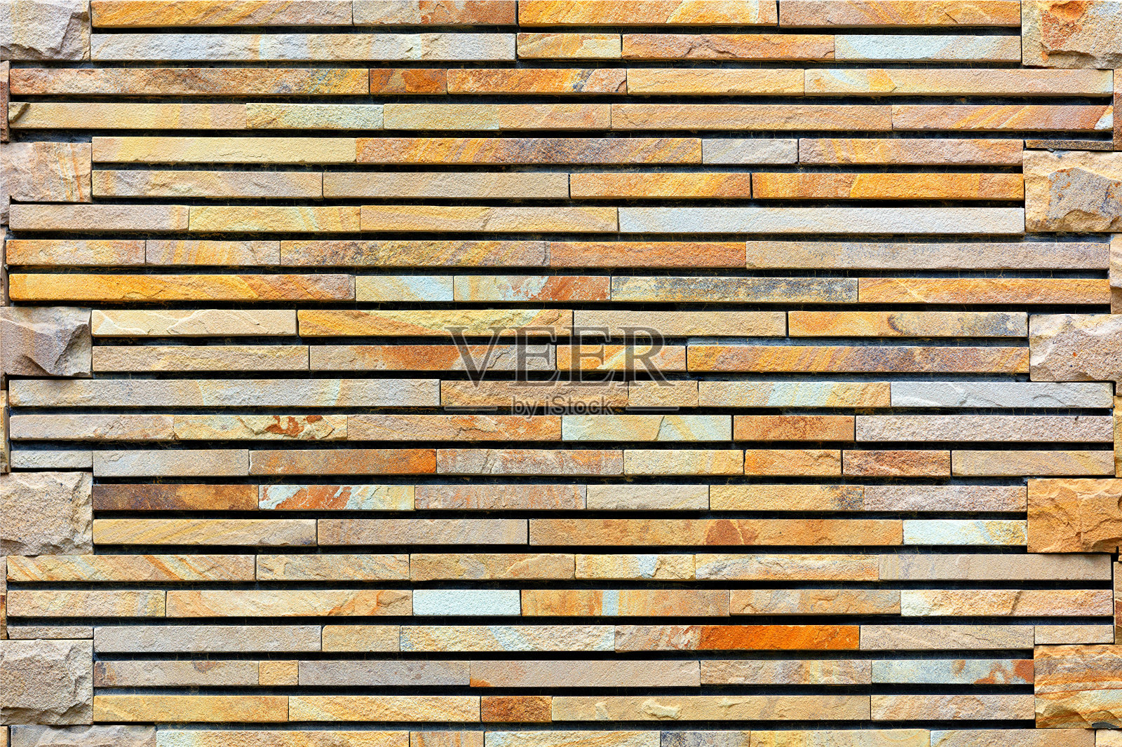 用加工过的平坦的金色砂岩砌成的石墙。照片摄影图片