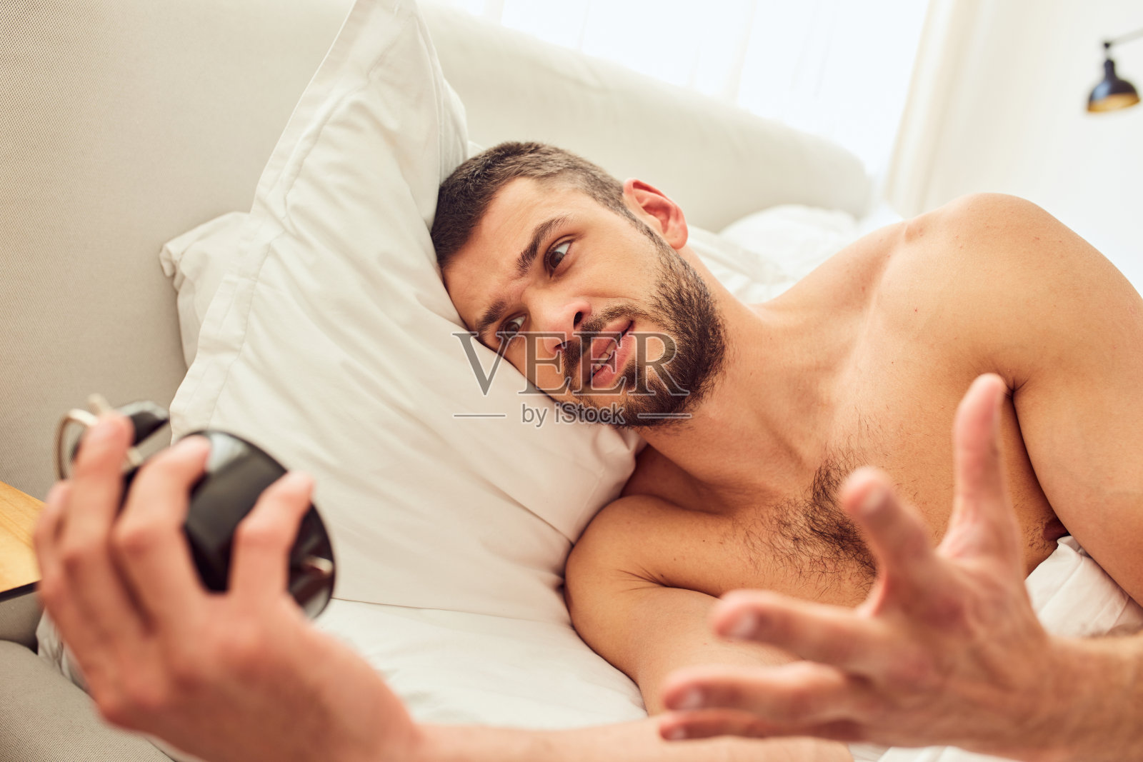 恼怒的年轻人在床上醒来照片摄影图片