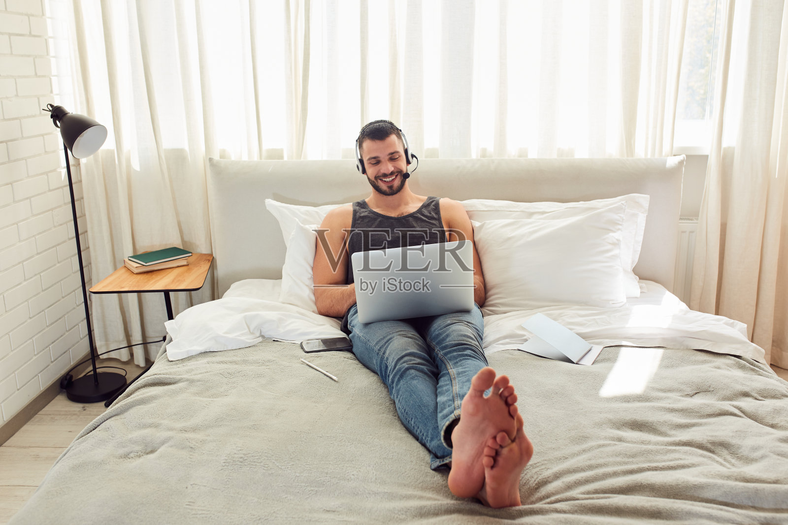 开朗的绅士在卧室里用现代笔记本照片摄影图片