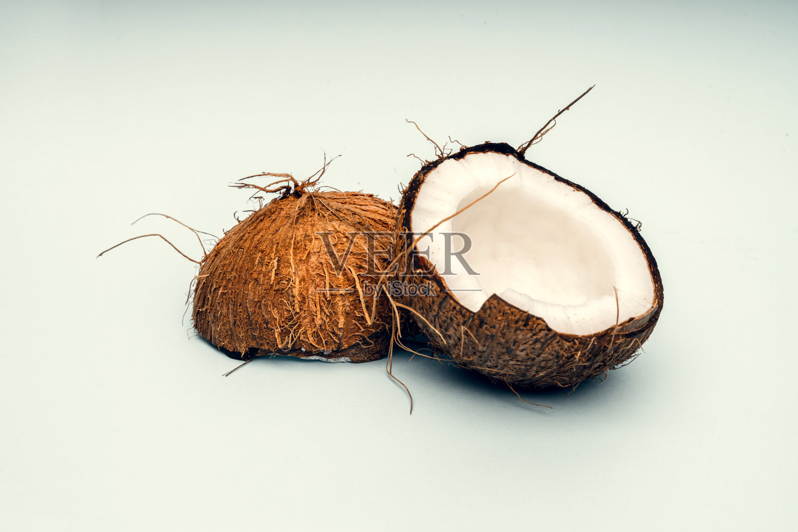 椰子的一部分在一个彩色的背景。关闭了。新鲜成熟的椰子碎成碎片。照片摄影图片