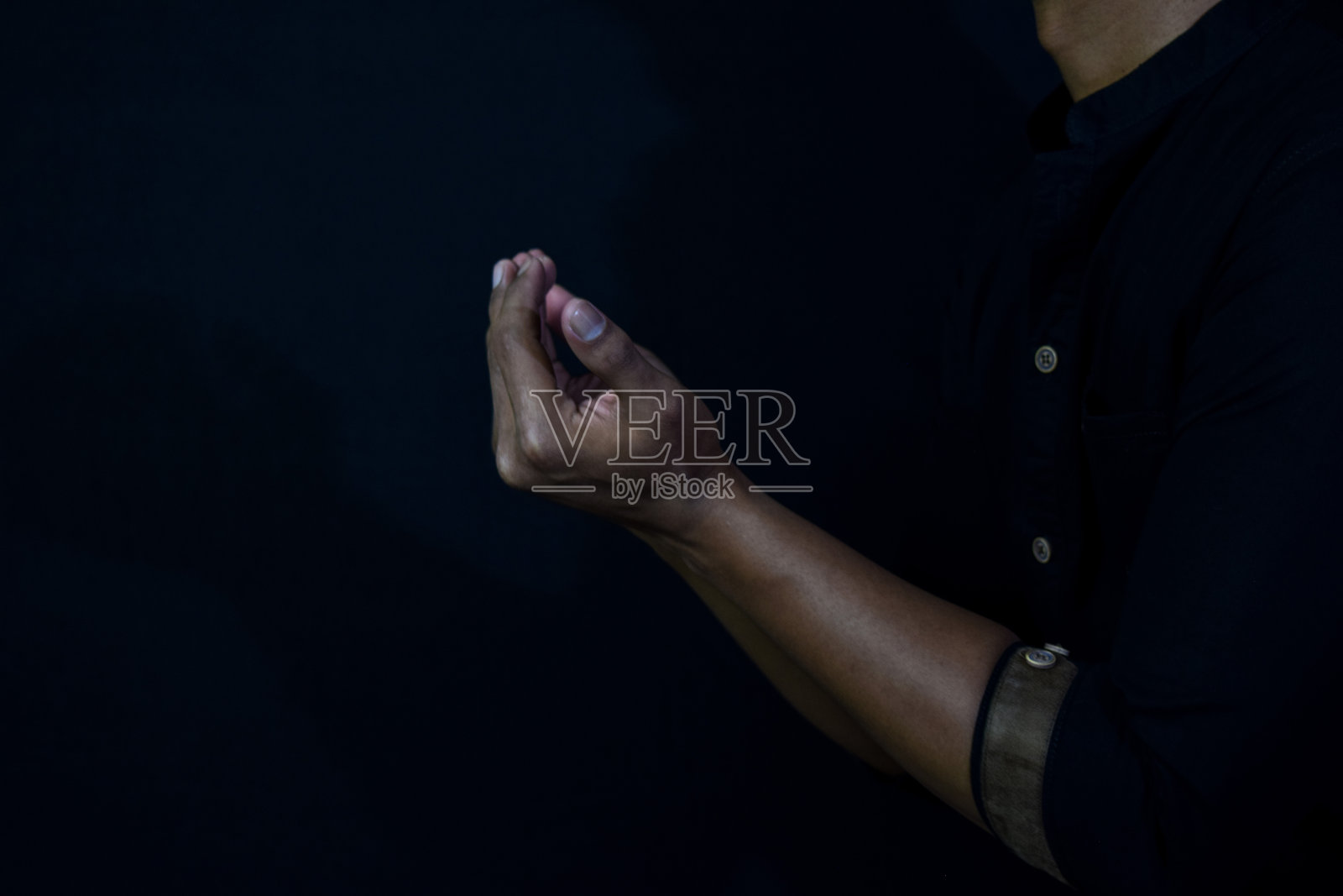 半长观看祈祷的穆斯林亚洲人。黑色背景上的伊斯兰祈祷概念。手指选择性聚焦照片摄影图片