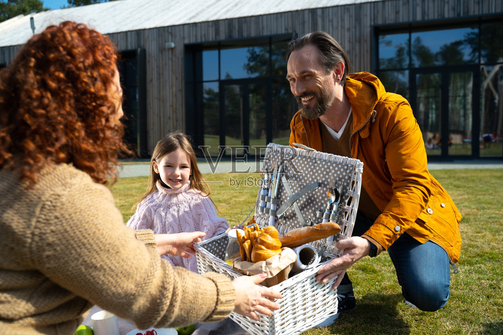 快乐的父母和他们可爱的女儿在户外野餐照片摄影图片