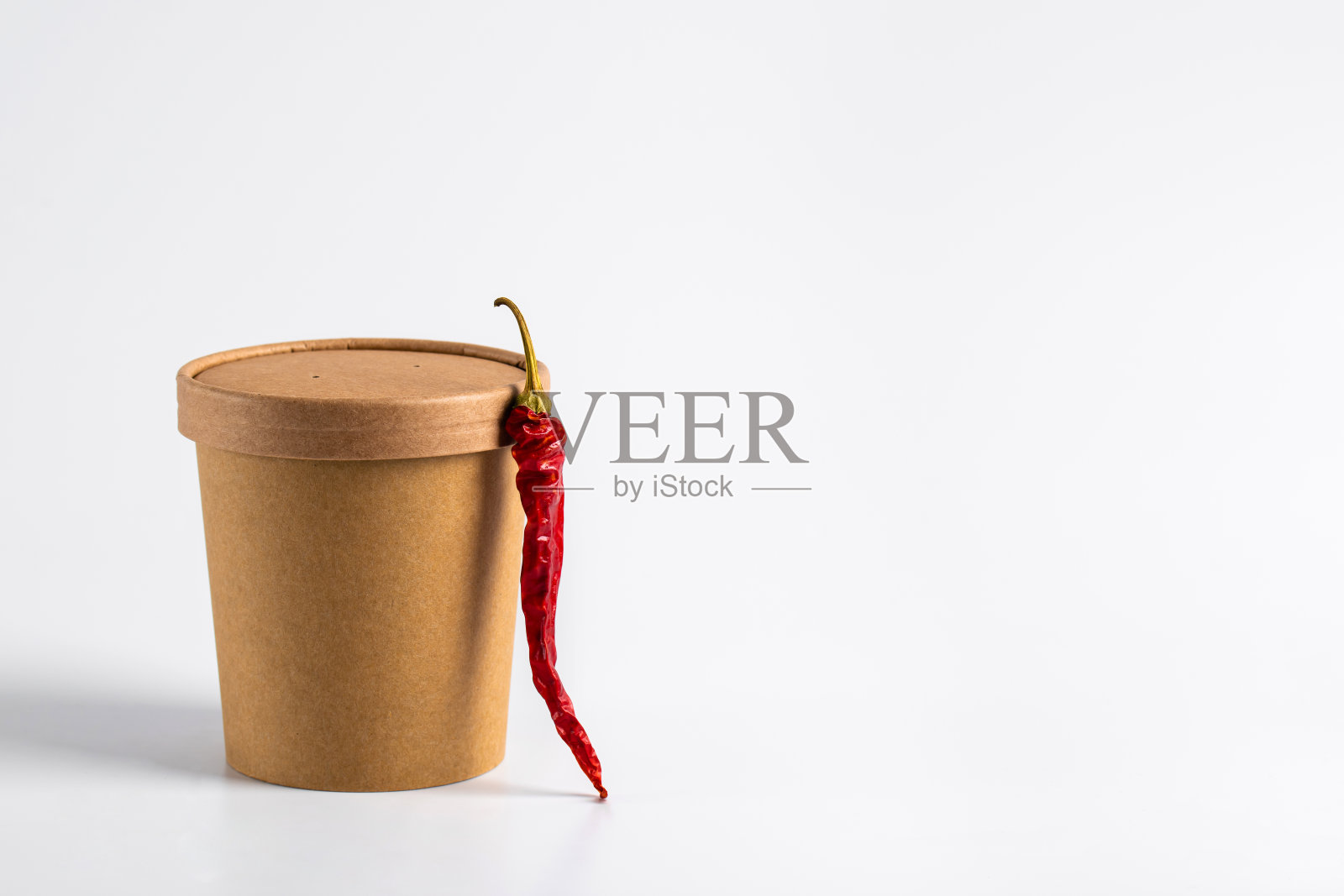 麻辣烫的汤装在工艺容器里，配上红辣椒和白色的背景。外卖食物。照片摄影图片