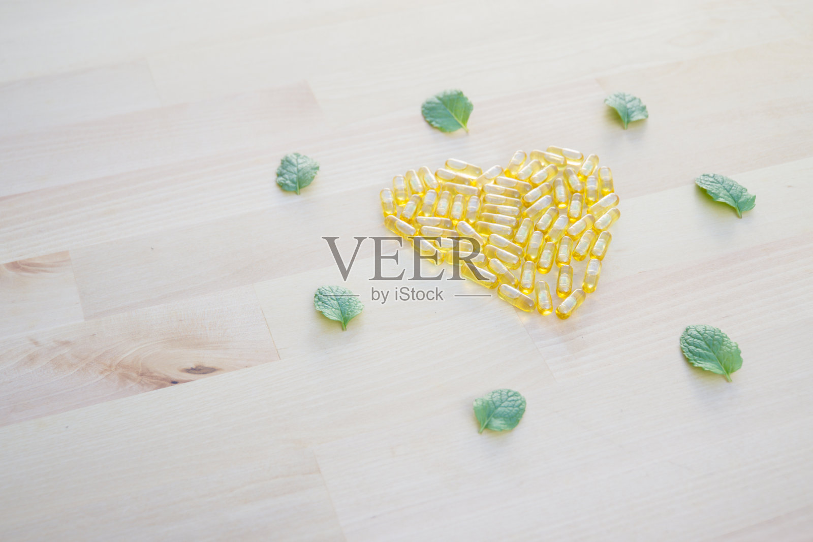 漂亮的排列成心形的黄色胶囊在木制的背景，健康的生活方式概念库存照片。照片摄影图片