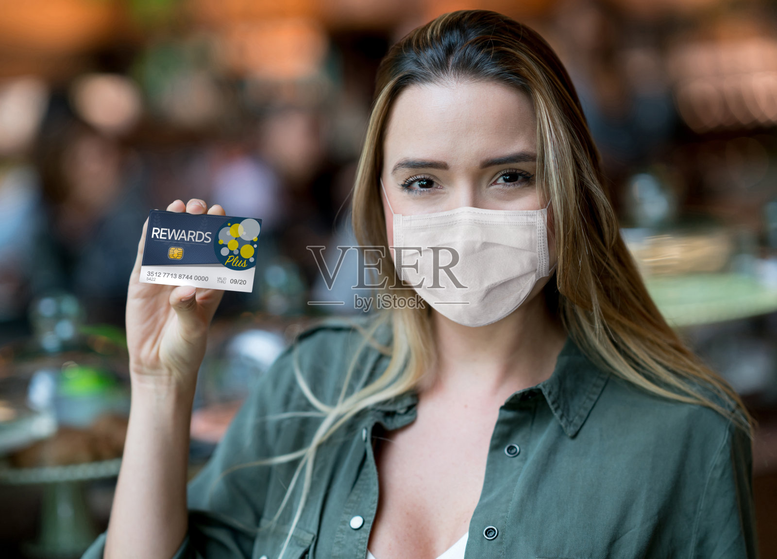 一个女人在超市拿着一张奖励卡，戴着口罩照片摄影图片