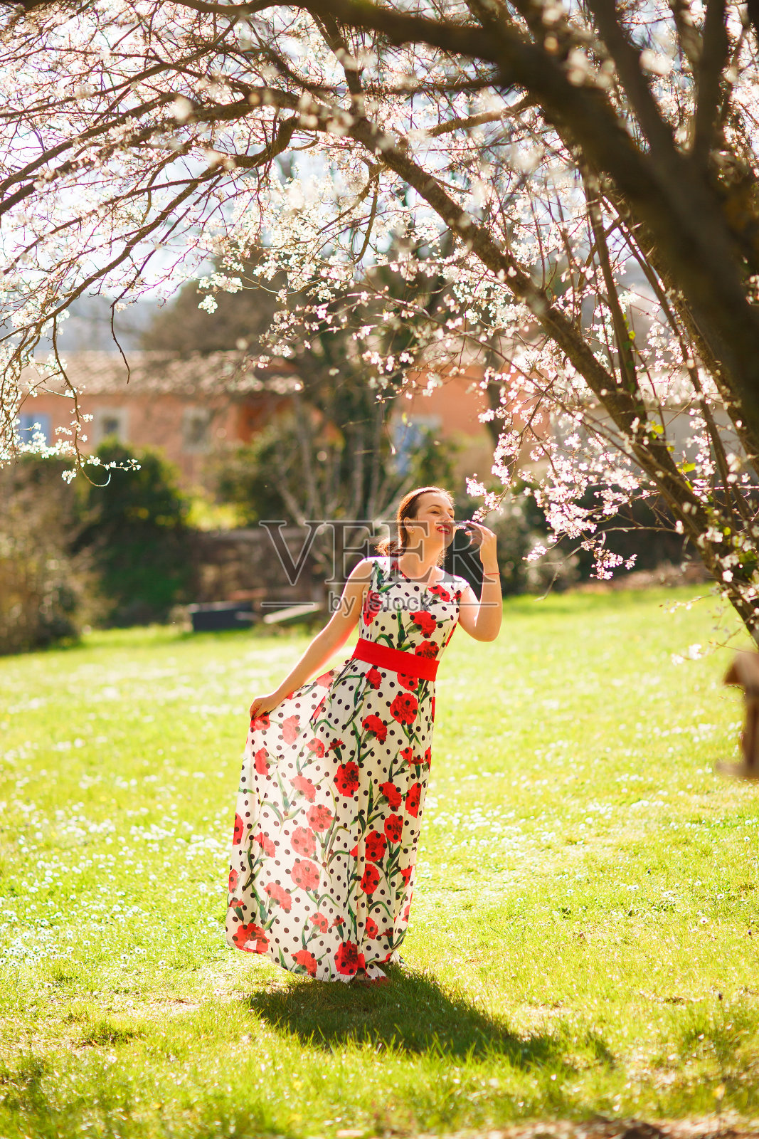 在春天的花园里，女孩穿着印花连衣裙。照片摄影图片