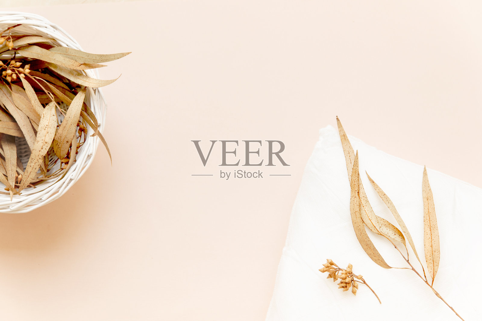 一个有桉树叶的篮子和一个上面有干树叶的枕头，珊瑚红的背景照片摄影图片