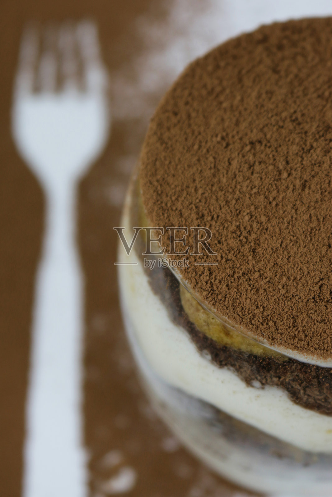 自制咖啡提拉米苏甜点的特写，马斯卡邦奶油，巧克力和海绵蛋糕女士的手指蘸浓咖啡，撒上可可粉，叉子模板俯瞰照片摄影图片