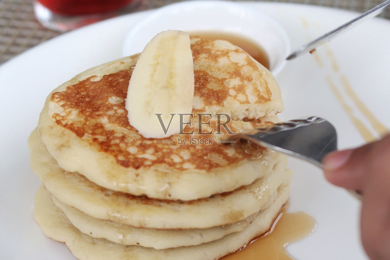 白色盘子上的一堆新鲜的苏格兰煎饼，上面放着香蕉片和枫糖浆照片摄影图片