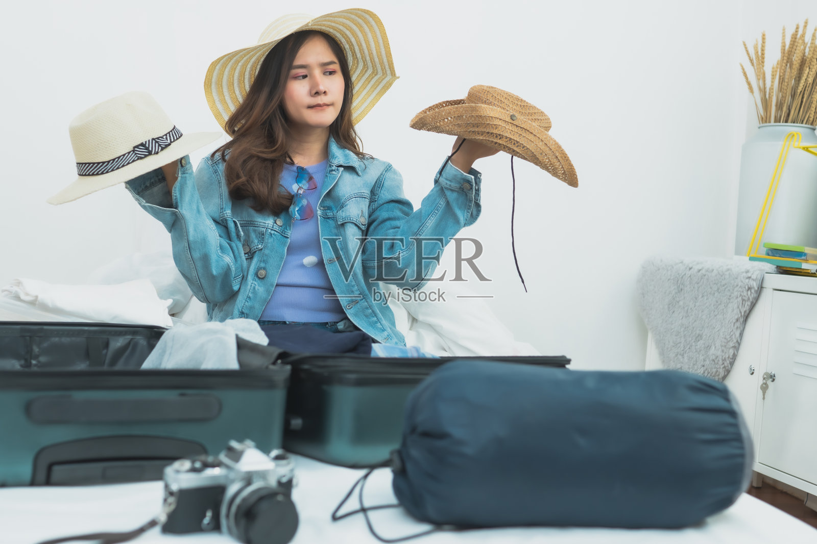 女人思考和选择帽子和准备物品进入手提箱旅行照片摄影图片