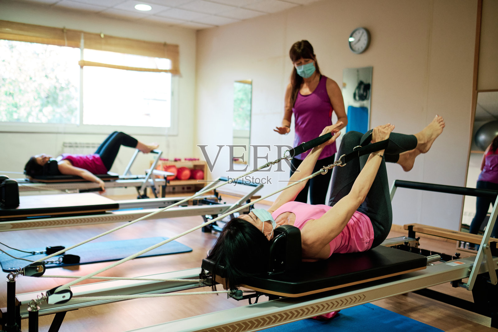 一群做锻炼、普拉提和瑜伽的成熟女性，保持社交距离，戴口罩照片摄影图片