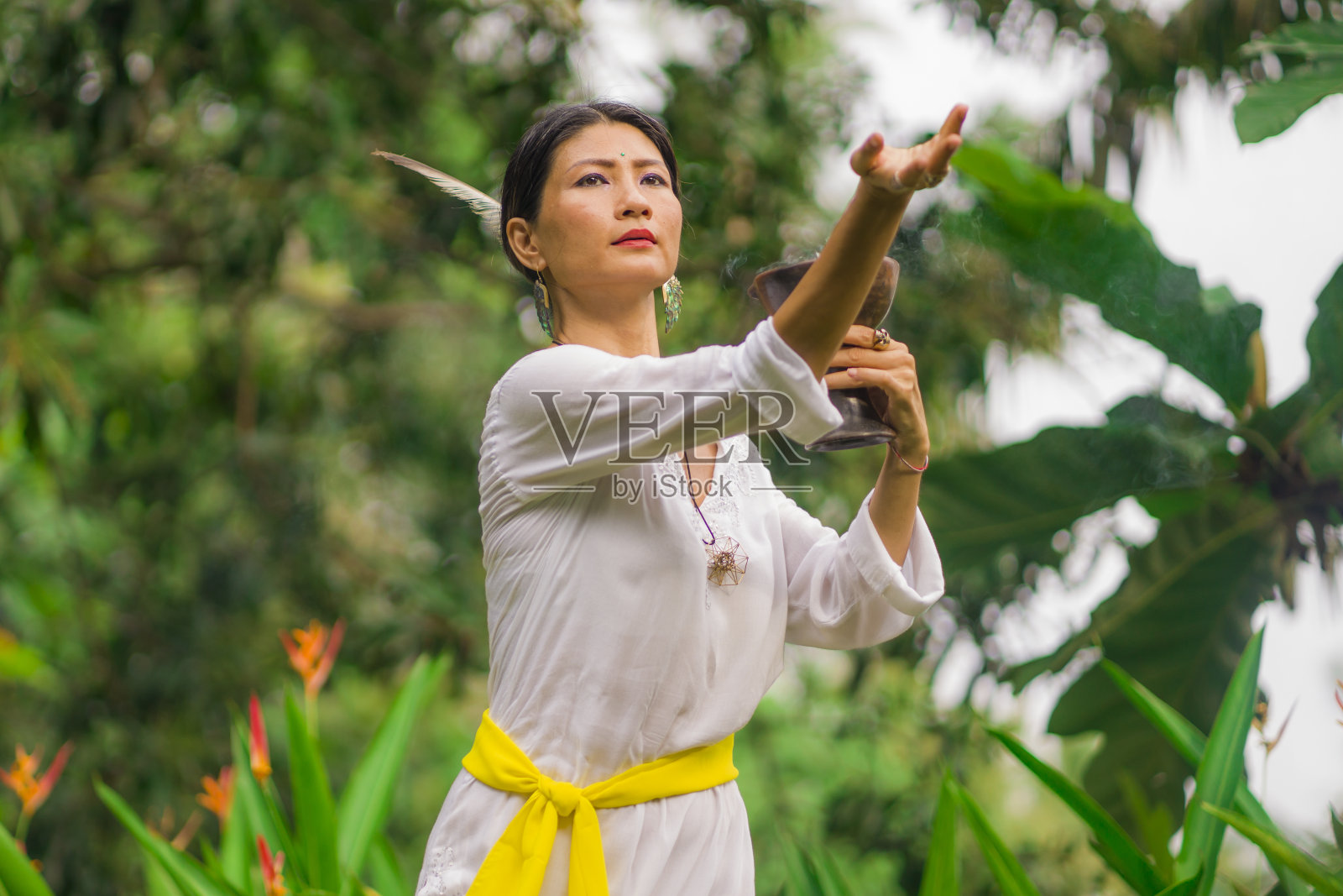 心灵和身体的连接-美丽和快乐的治疗师亚洲女人拿着香杯做仪式的传统治疗舞蹈在绿色热带森林的健康和健康的生活方式照片摄影图片