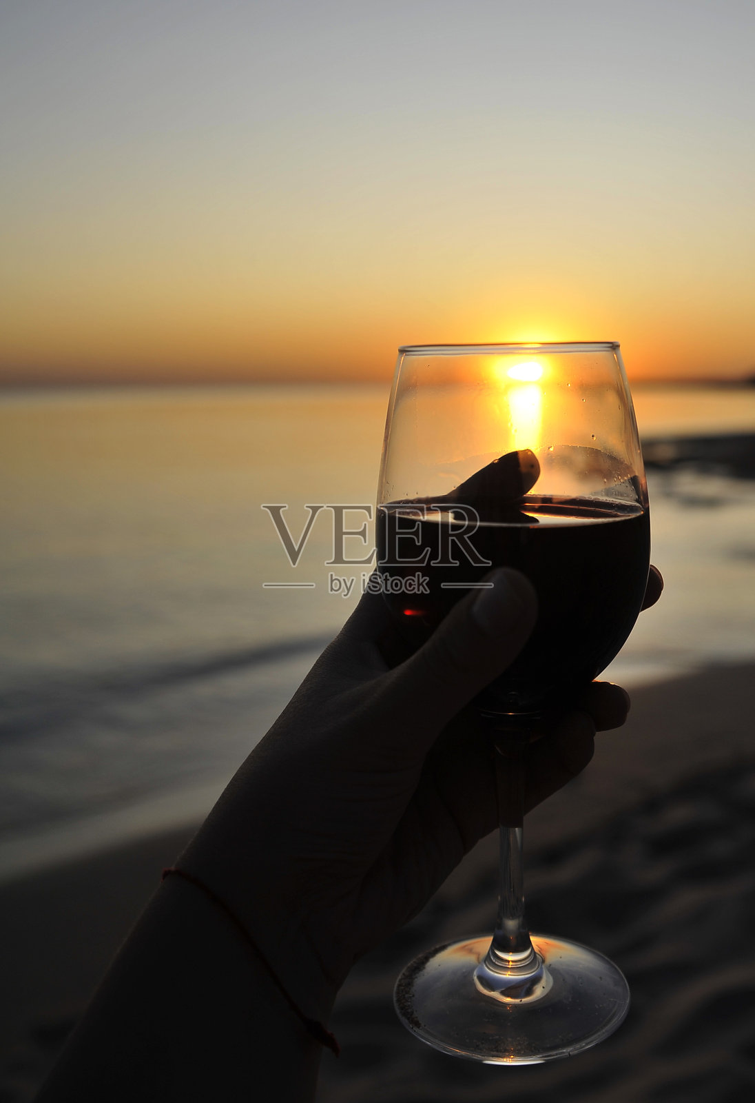 日落时分，海滩上的红酒酒杯。浪漫的概念。照片摄影图片