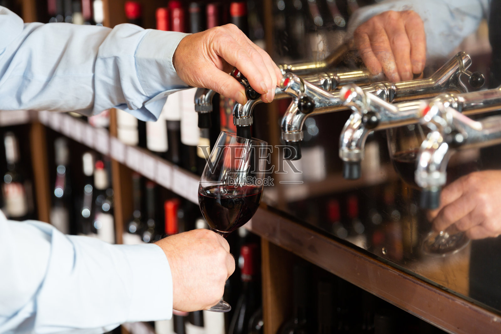 酒保的手从水龙头里倒红酒照片摄影图片