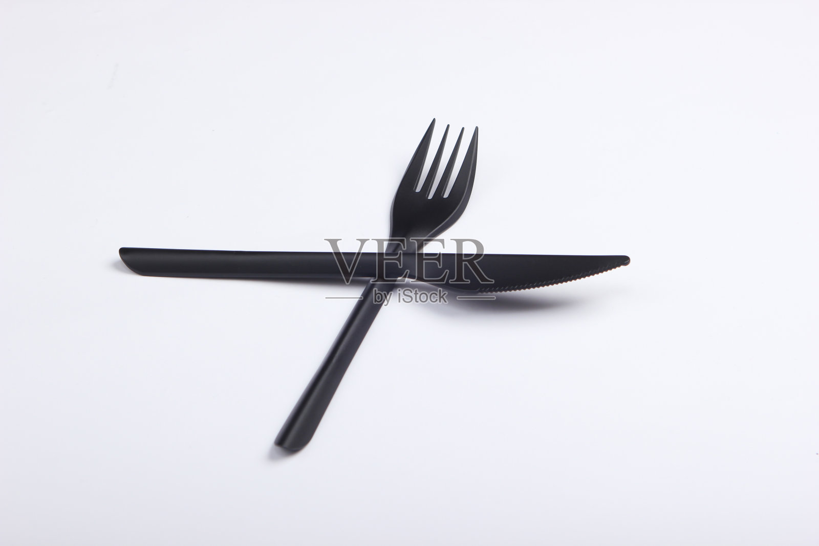 白色背景上带叉的黑色塑料刀。照片摄影图片