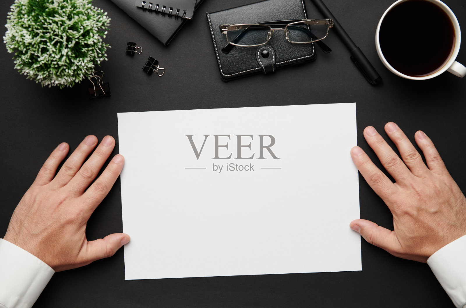 俯视图的商人的手工作。现代黑色的办公桌上有笔记本、钢笔和很多东西。平铺表布局。为文本复制空间。照片摄影图片