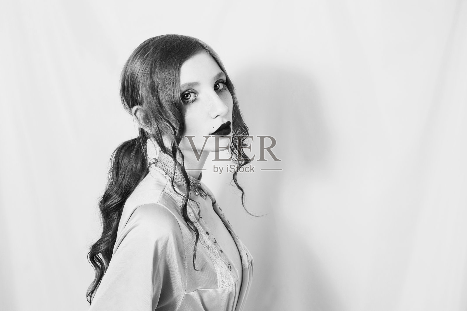 黑白艺术摄影单色，性感的女孩与头发聚集在一个马尾辫手里拿着一朵丁香花。哥特式纹身模型在性感内衣与一个苗条的腰照片摄影图片