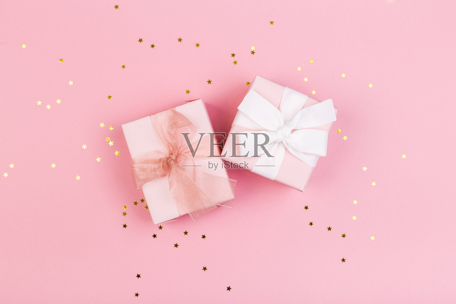 礼物或礼品盒和星星纸屑在粉红色的桌子上从上面。生日、母亲节或婚礼用的平面构图。照片摄影图片