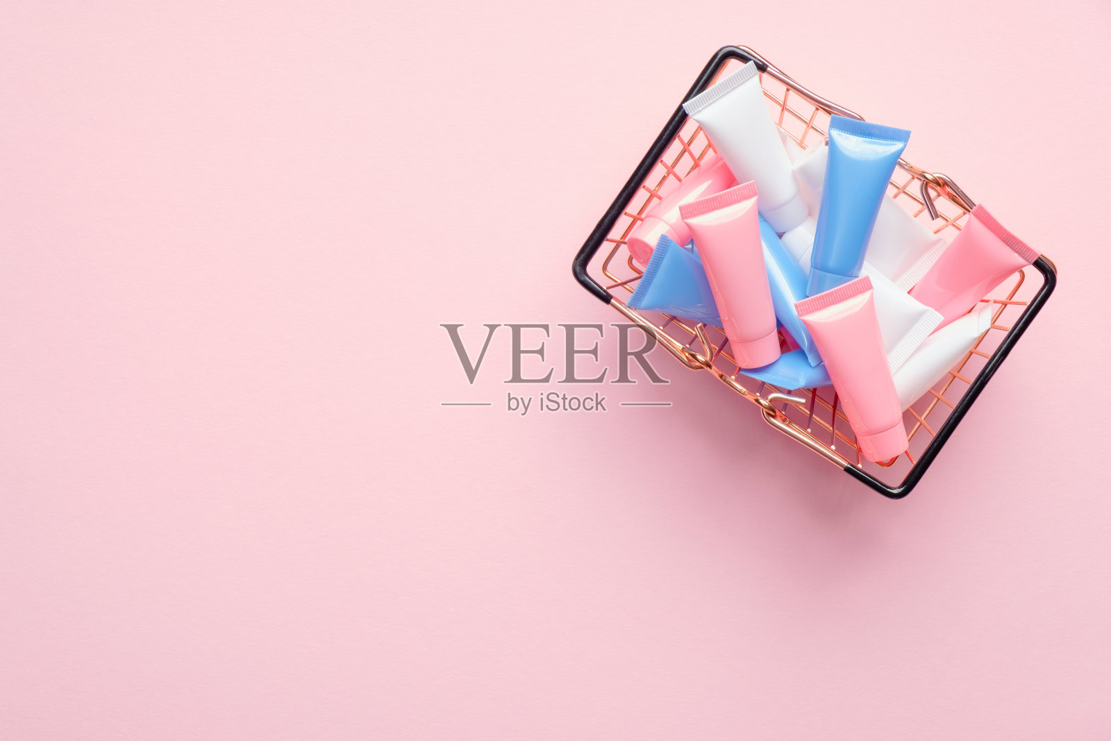 购物篮子里满是粉色背景的彩妆管。化妆品商店的横幅设计。平躺，俯视图照片摄影图片