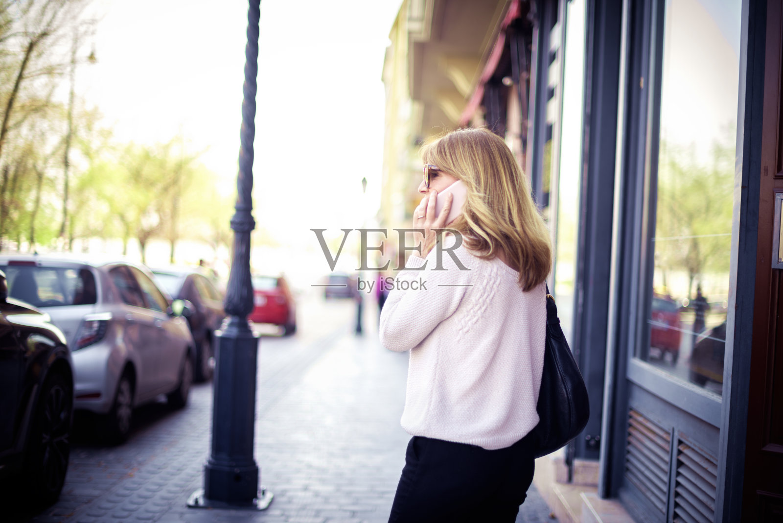 一个自信的女人一边走在街上一边用手机和别人聊天照片摄影图片