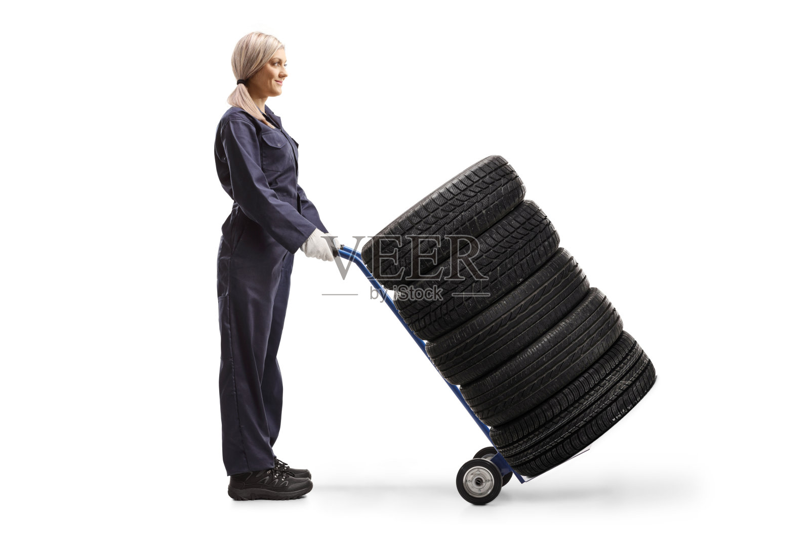 女汽车修理工站在一辆手推车上拿着轮胎照片摄影图片