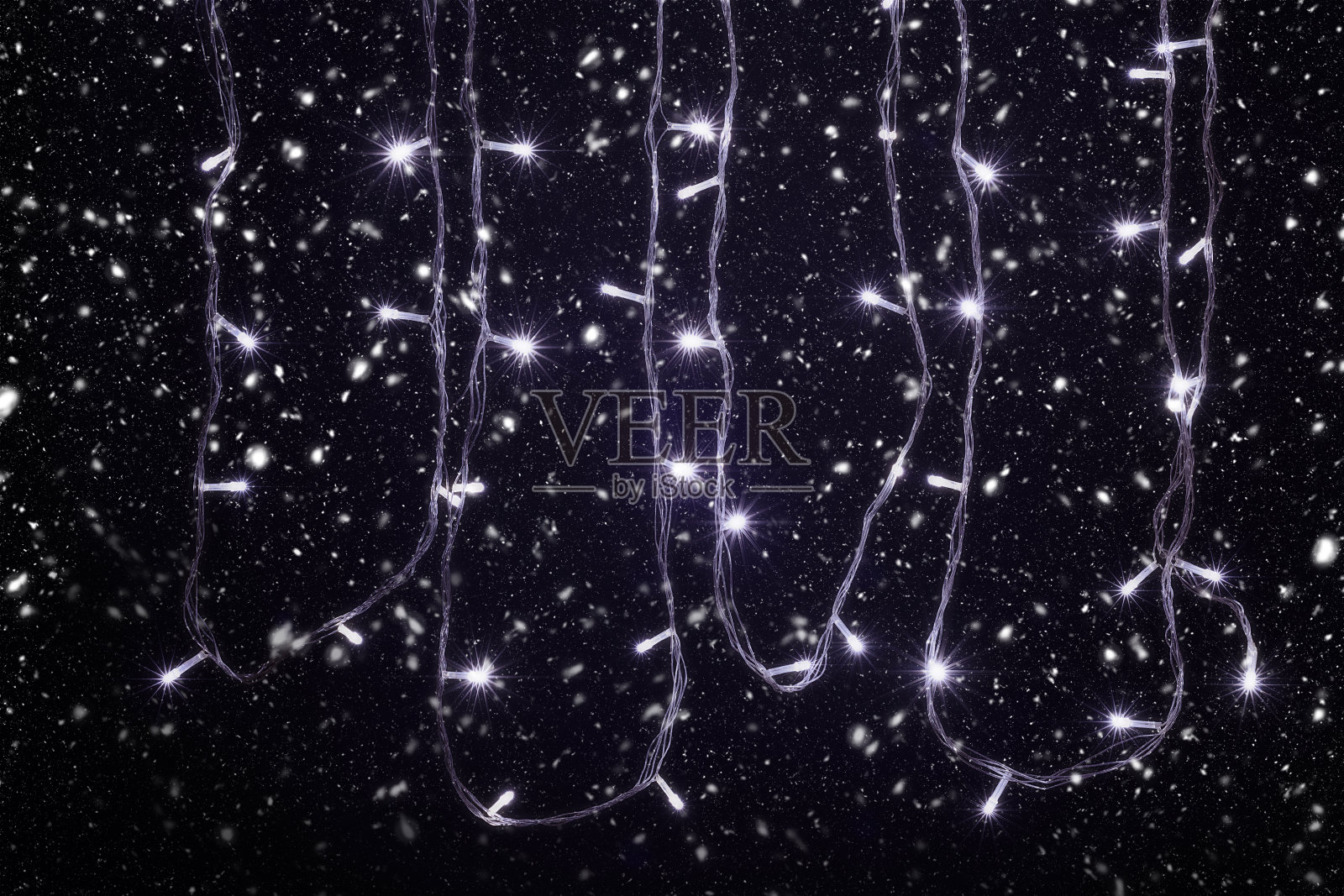 圣诞和新年装饰灯，花环在下雪与小Led灯闪烁在黑色的背景。照片摄影图片