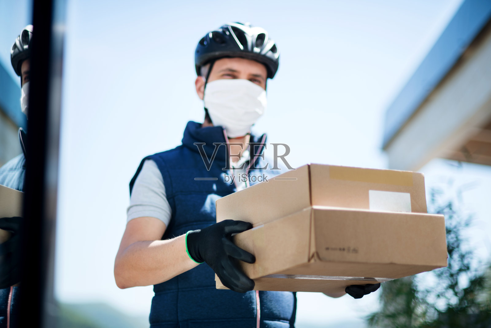 快递员带口罩递送包裹、冠状病毒和检疫概念。照片摄影图片