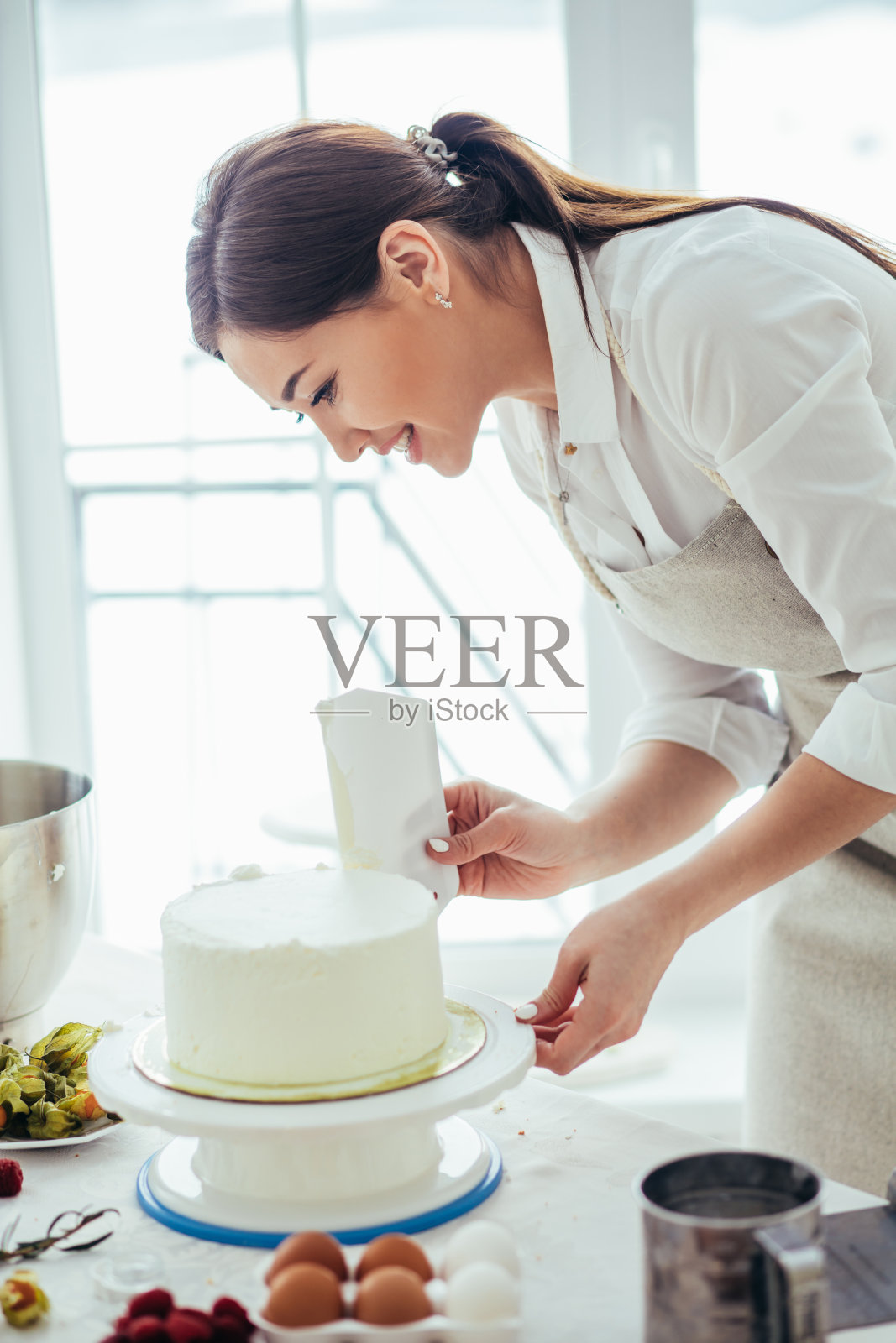 亚洲女孩，用一把长刀削平蛋糕的边缘和顶部照片摄影图片