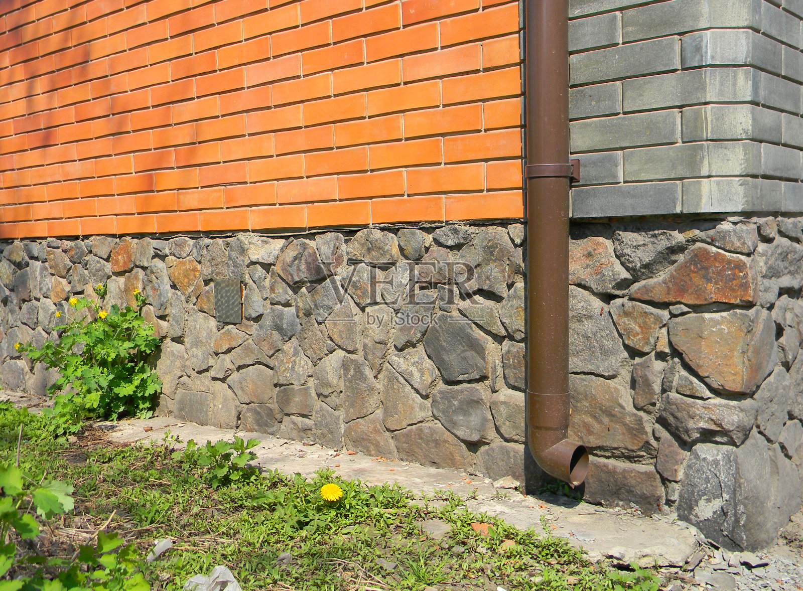 屋顶排水沟落水管与砖房基础墙无排水。湿的基础。照片摄影图片