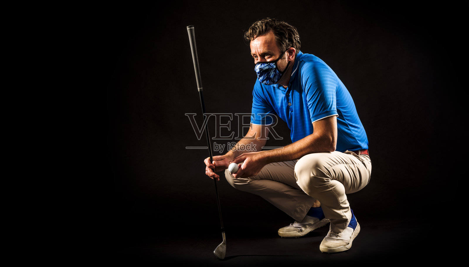 戴着COVID-19面罩的高尔夫球手研究球进入洞的轨迹照片摄影图片