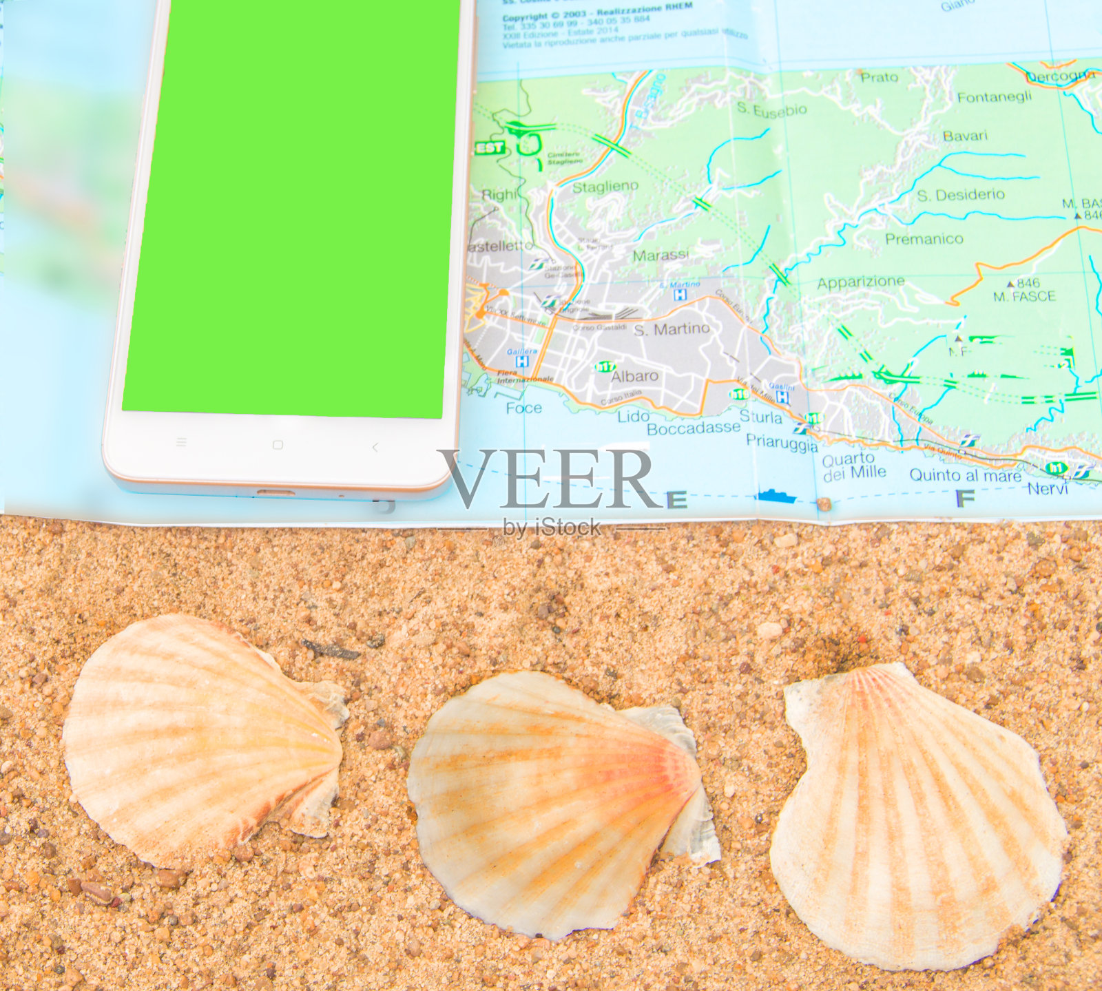 智能手机上的绿色屏幕chromakey旅游地图用贝壳放在沙滩上，手机屏幕可以替换，旅游概念，俯视图照片摄影图片