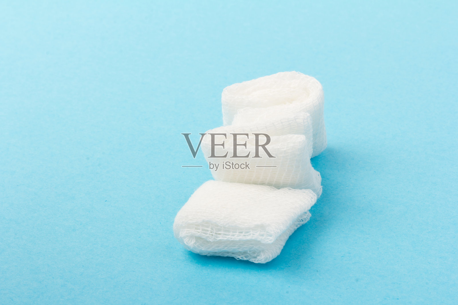 蓝色背景上的白色纱布垫。牙科手术材料。近距离照片摄影图片