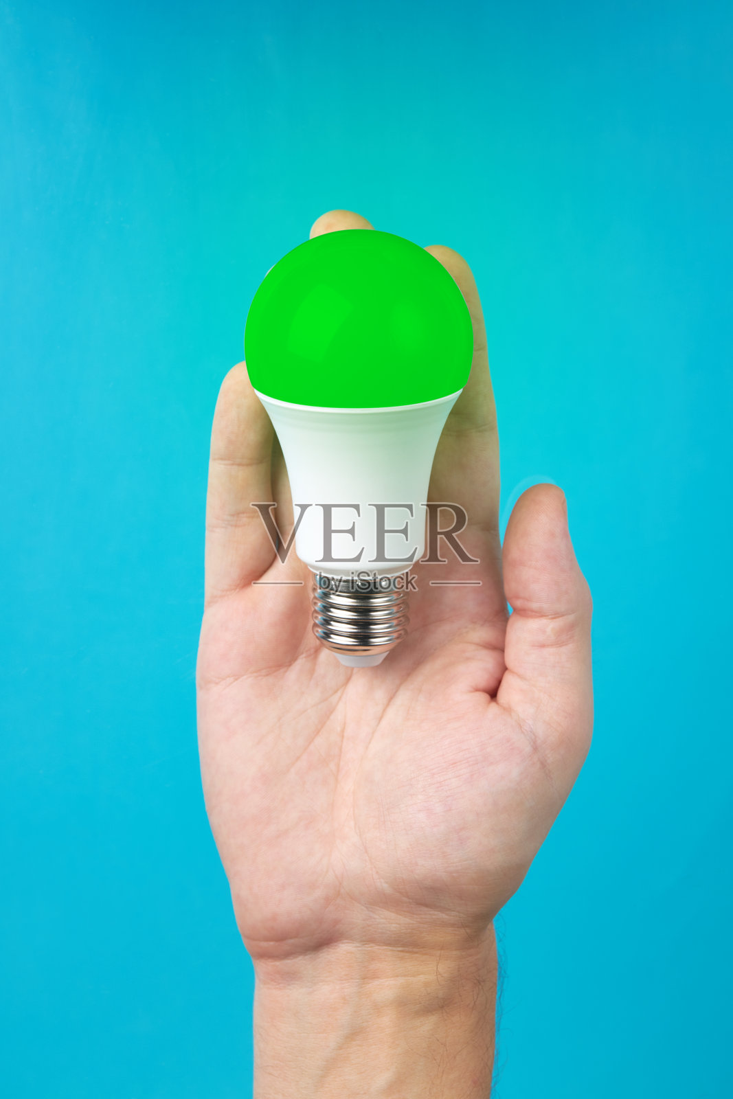 省电节电理念。手握环保灯泡标志。使用替代技术。创新理念的概念。蓝色背景。垂直的照片。照片摄影图片
