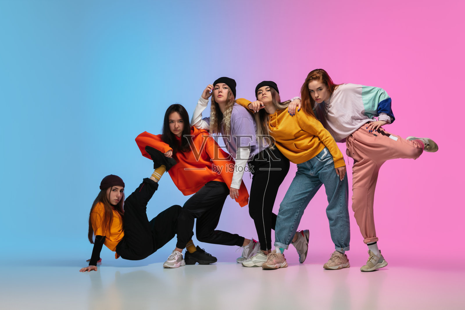 一群舞者，男孩和女孩跳舞嘻哈在霓虹灯梯度工作室的背景时尚的衣服。照片摄影图片