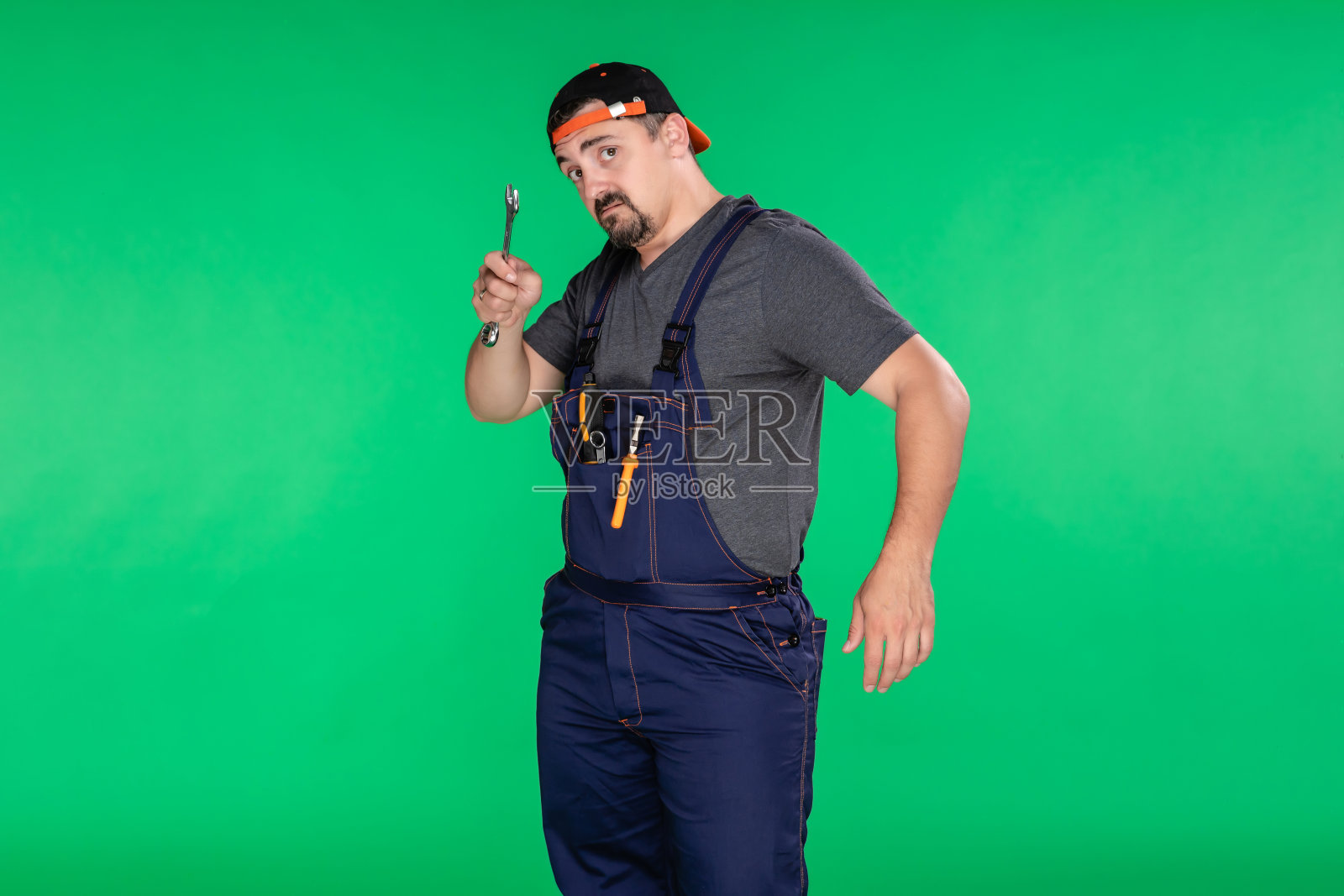 不高兴的机修工看着绿色背景的相机照片摄影图片