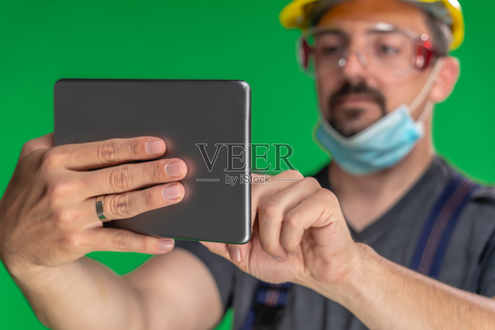 建筑工人用N95防护面罩和头盔使用数码平板电脑照片摄影图片