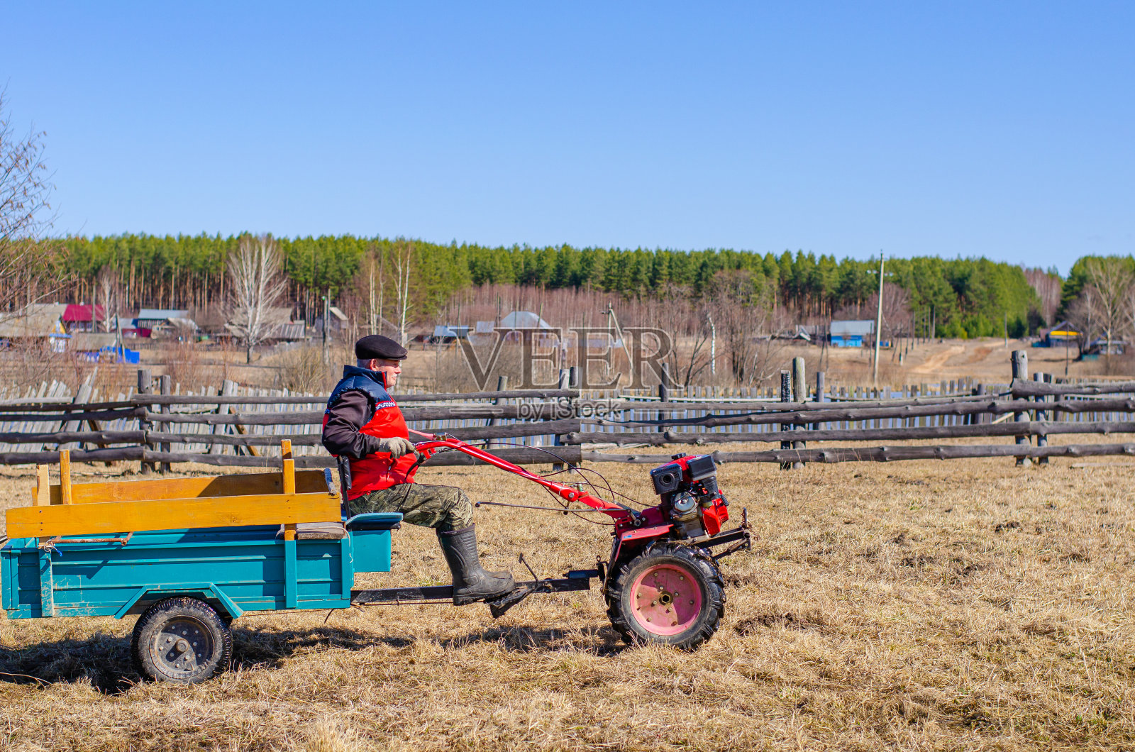 农民在村里的田地里开着红色的微型拖拉机。春与收获概念，新作物孤立。照片摄影图片