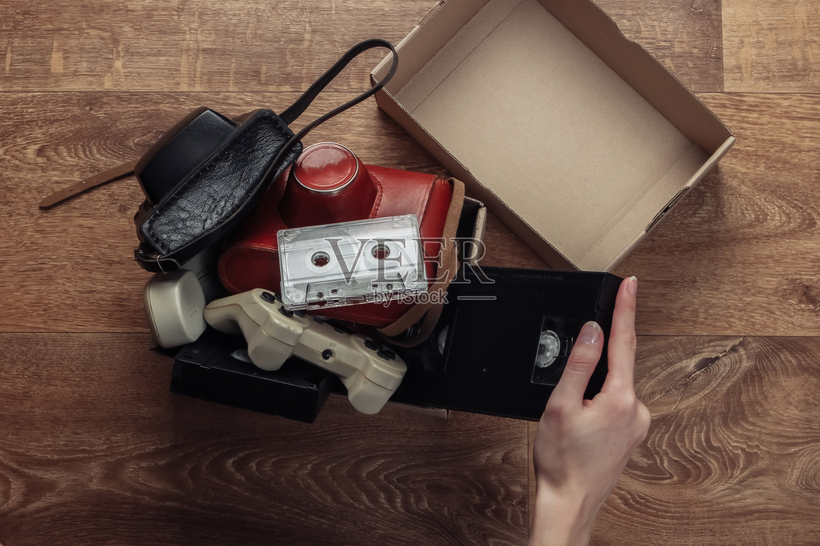 女性的手将复古物品堆放在木地板上的纸箱里。古玩,古董。俯视图照片摄影图片