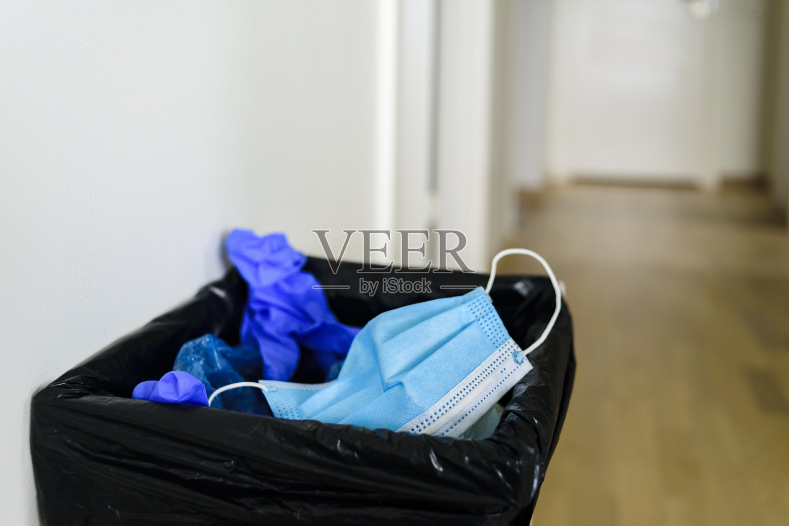 废物箱内装有医疗垃圾——走廊内的口罩、手套照片摄影图片