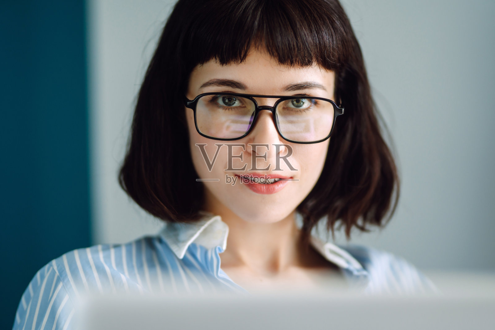 年轻女子坐在现代的客厅里用笔记本电脑工作。照片摄影图片