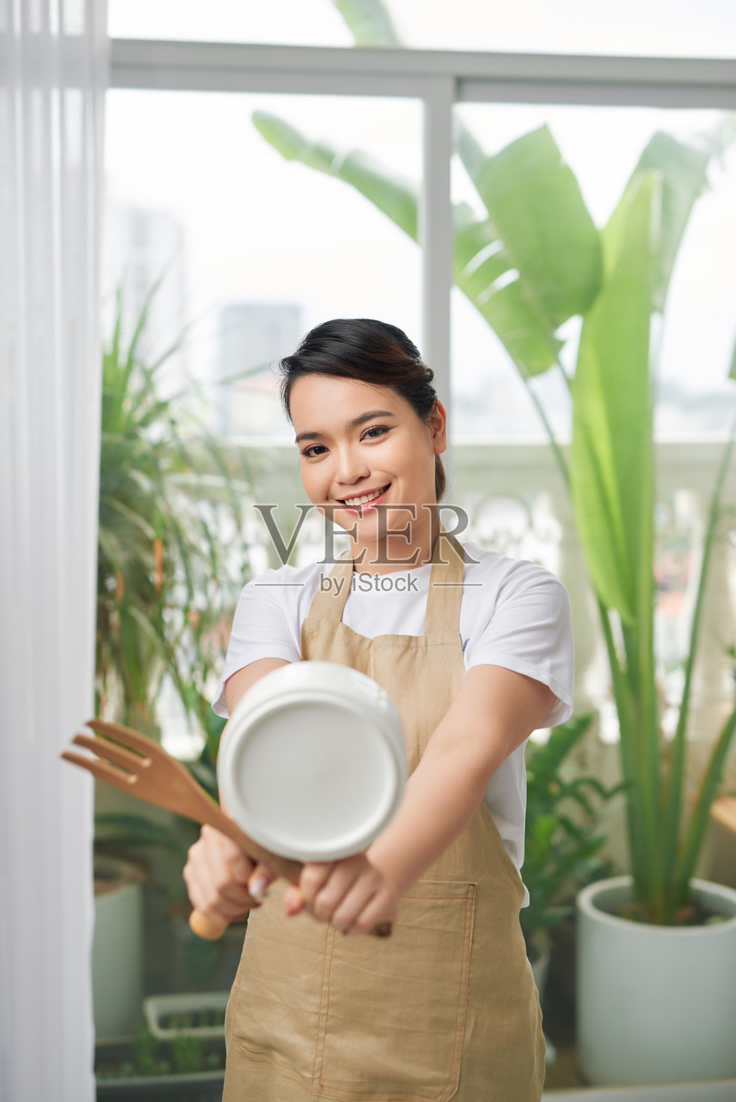 快乐家庭主妇捧着平底锅，管家女佣服务理念照片摄影图片